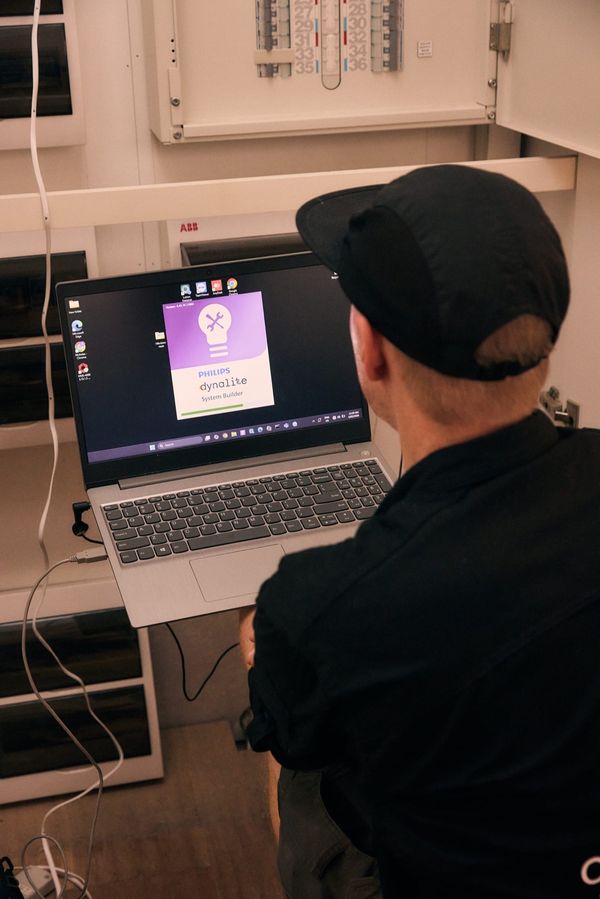 One Out Electrical technician programming a Philips Dynalite smart home system using a laptop