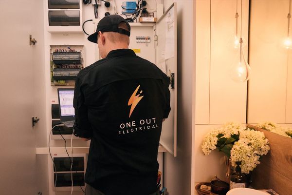 One Out Electrical electrician programming a Dynalite smart home panel adjacent to pendant light installation