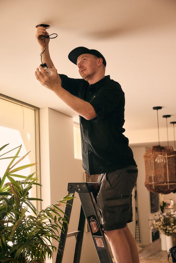 Electrician wiring a ceiling light fitting during a residential lighting installation in Hobart, Tasmania