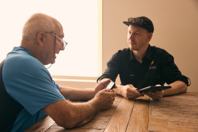 One Out Electrical electrician going over a job quote with a customer using a tablet