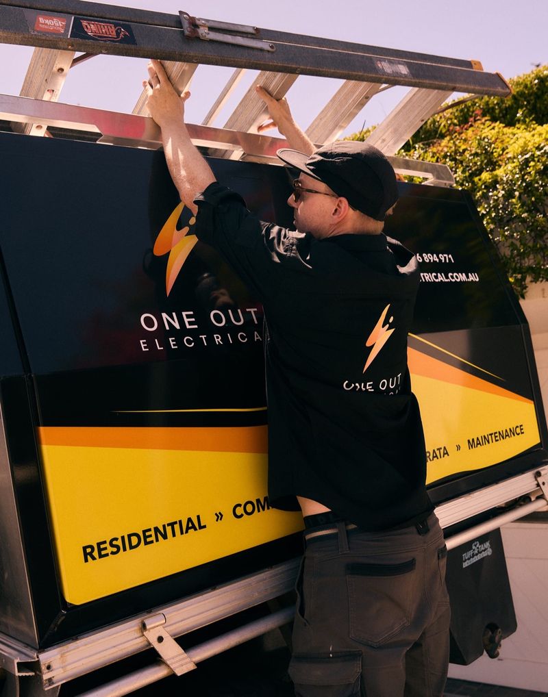 One Out Electrical electrician securing a ladder on the branded service ute before heading to a job