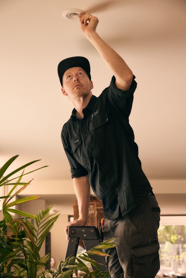One Out Electrical electrician installing a recessed LED downlight in a modern residential ceiling